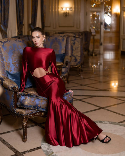 Woman in a red dress sitting on an ornate chair in a luxurious room.