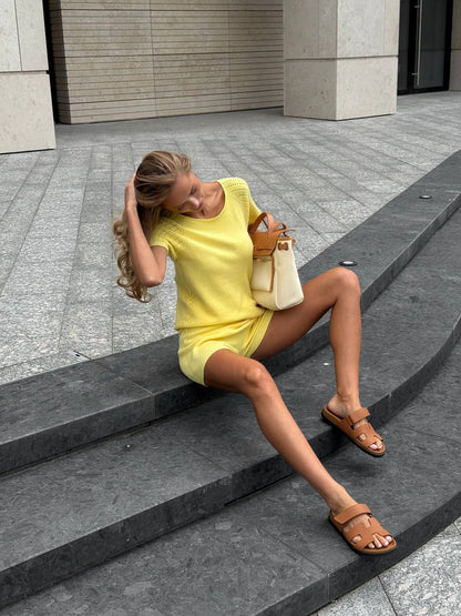 Woman in a yellow outfit sitting on steps outdoors
