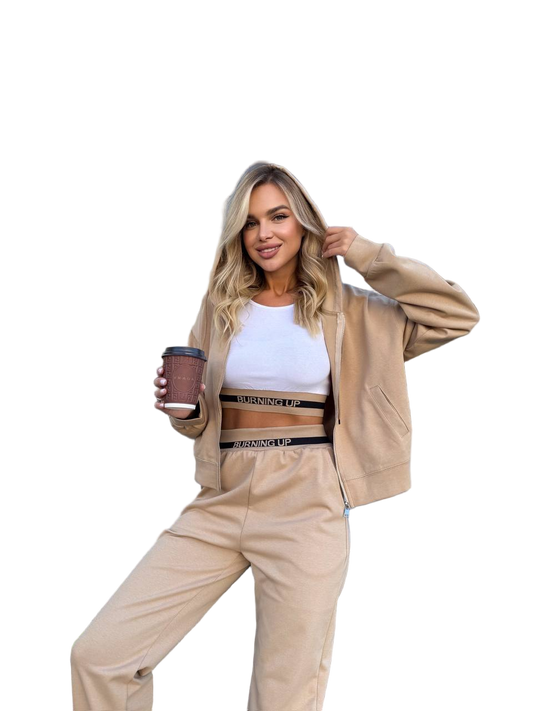 Woman wearing a beige tracksuit holding a coffee cup on a white background