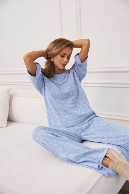 Woman wearing a light blue sweater and pants sitting on a white couch.