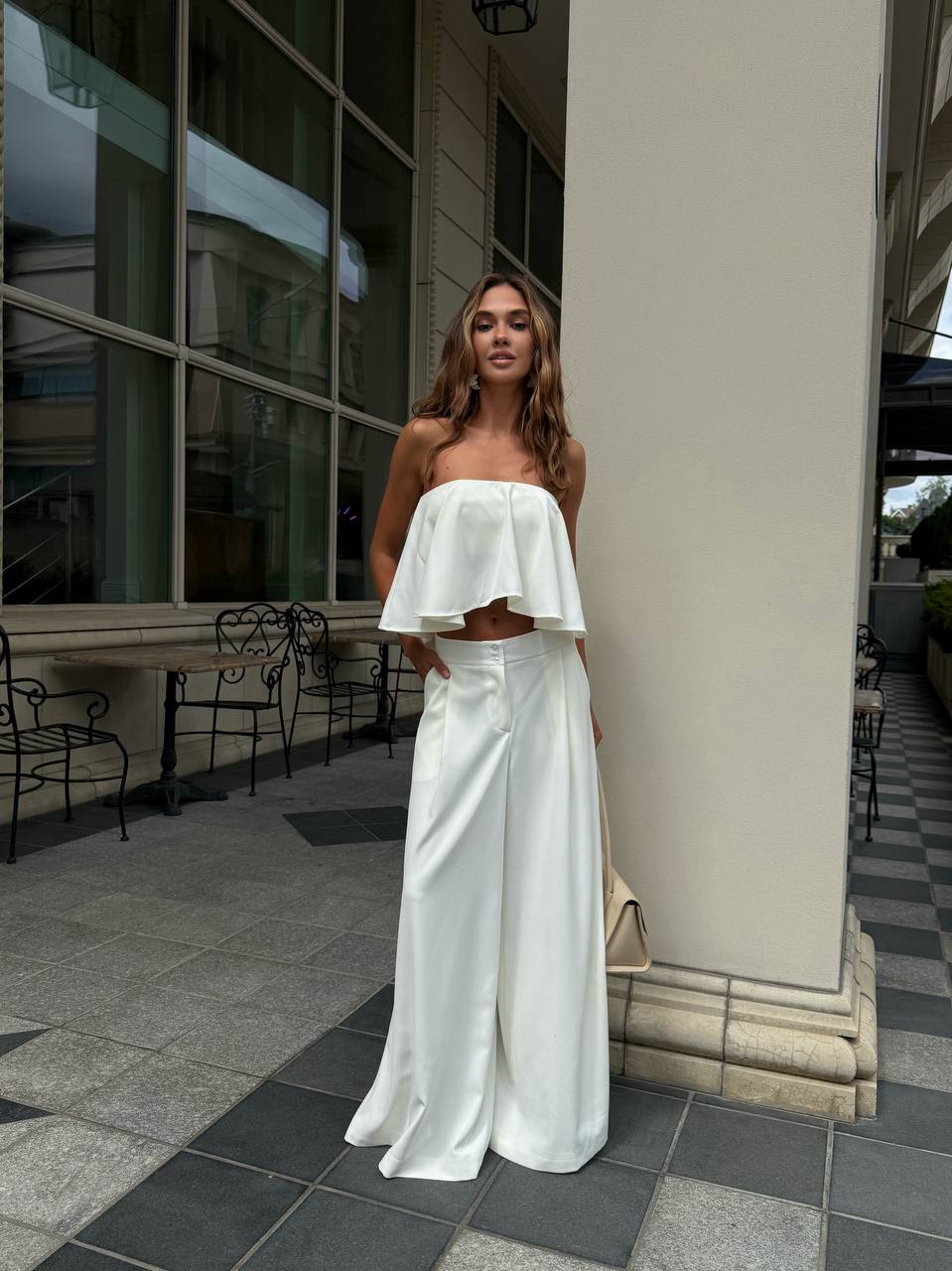 Woman in a white outfit standing outdoors near a building.