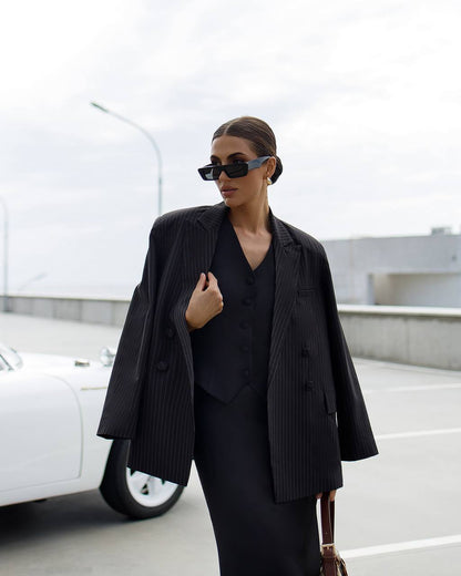 Person wearing a black outfit with sunglasses in front of a white vehicle