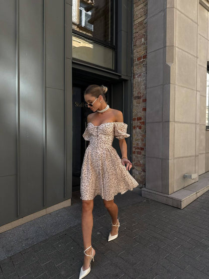 Woman in a floral off-shoulder dress walking on a city street.