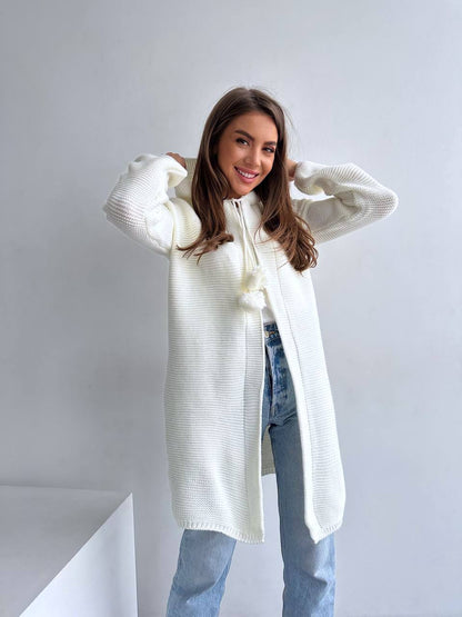 Woman wearing a long white sweater against a plain background