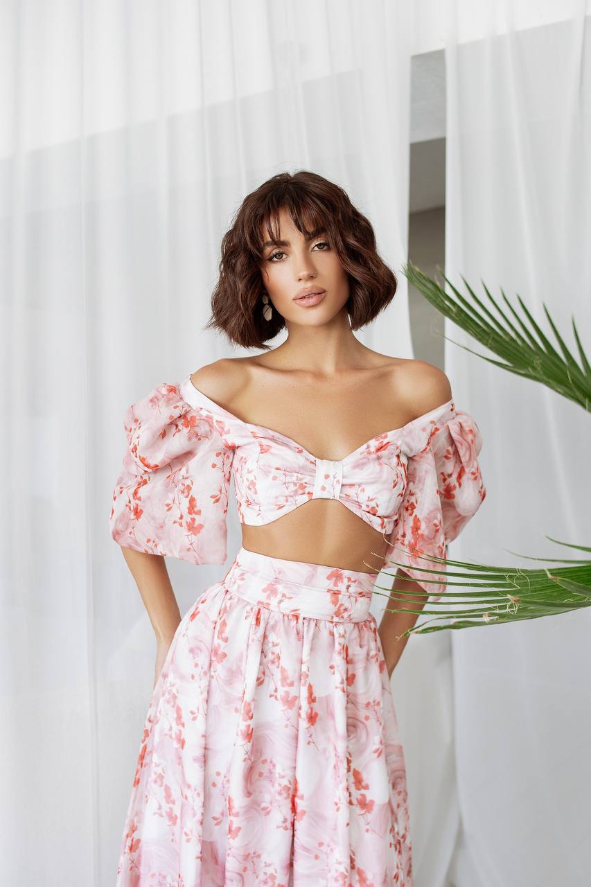 Woman wearing a pink floral off-shoulder dress with a white background