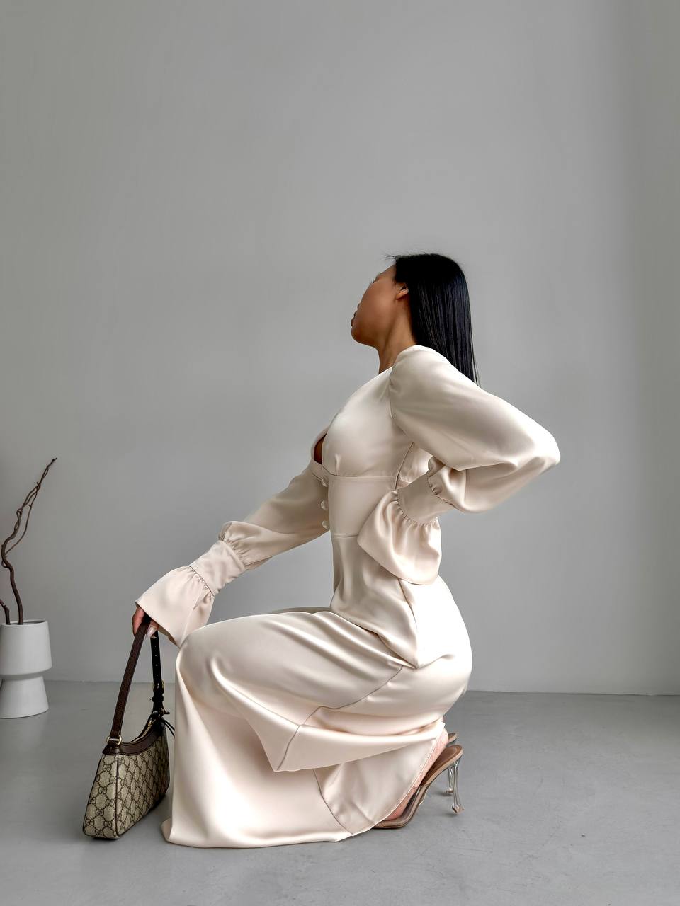 Woman in a white satin dress sitting on the floor with a gray background