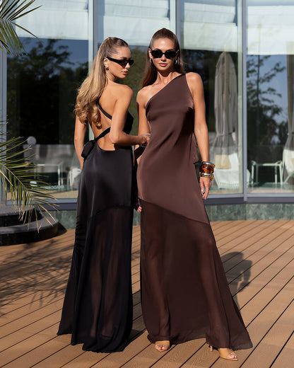 Two women in elegant evening gowns standing on a wooden deck.