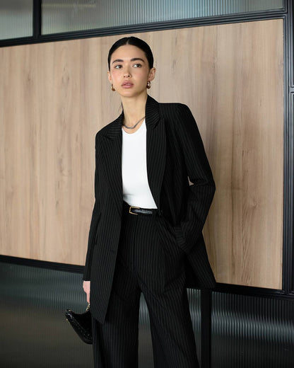 Woman in a black pinstripe suit standing in an office setting