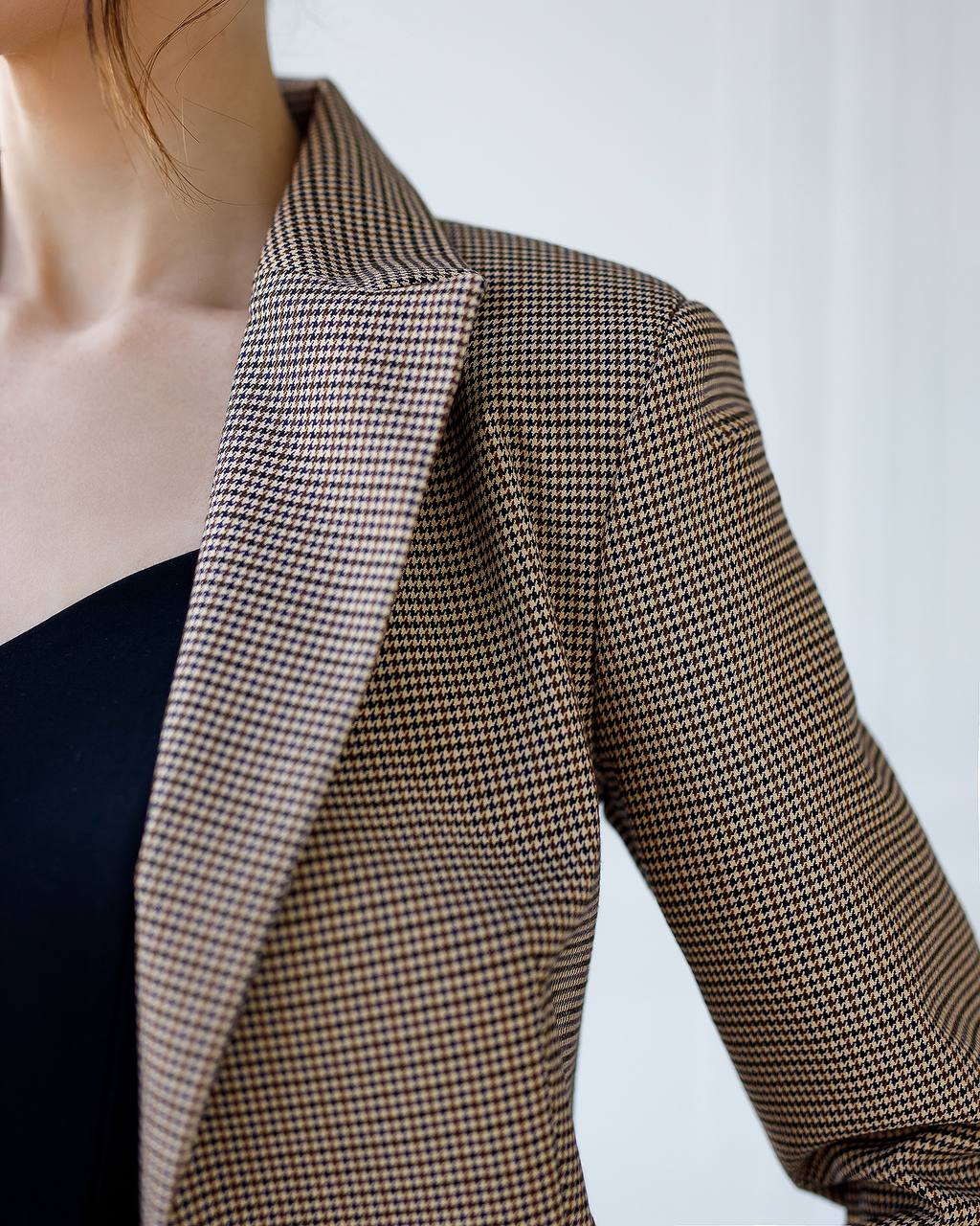 Houndstooth patterned blazer worn by a person on a plain background
