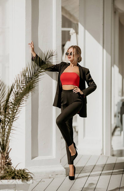 Woman in a red top and black pants standing against a white architectural background