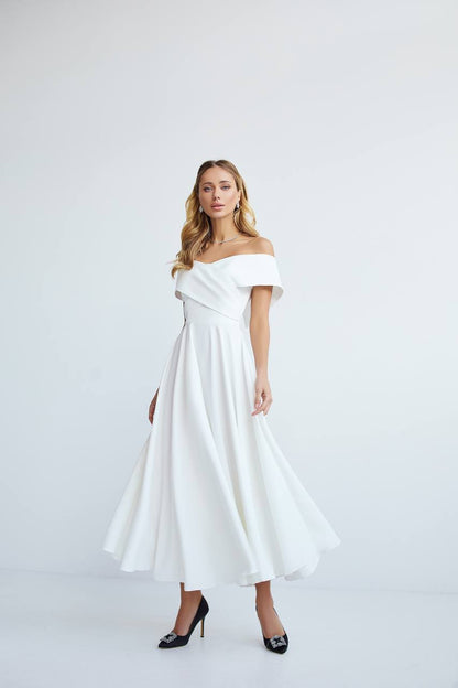 Woman wearing a white off-shoulder dress on a light gray background