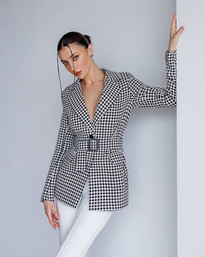 Woman wearing a black and white checkered blazer against a gray background