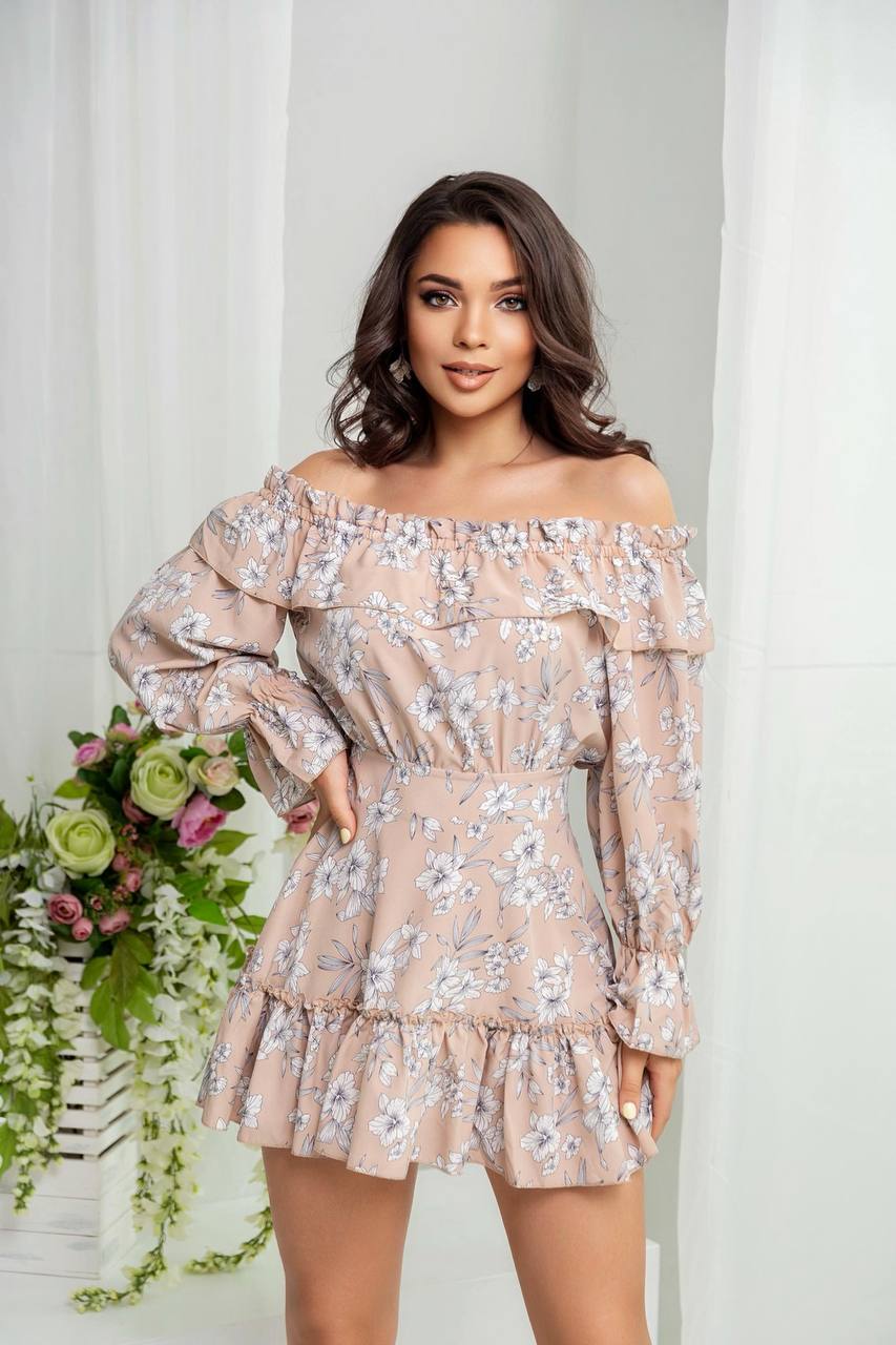 Woman wearing a floral off-shoulder dress with a white curtain and flowers in the background