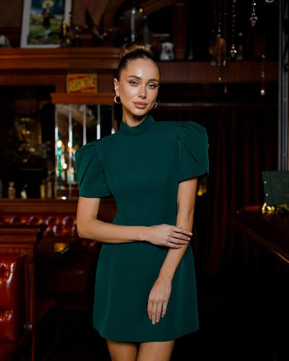Woman in a green dress standing in a bar setting
