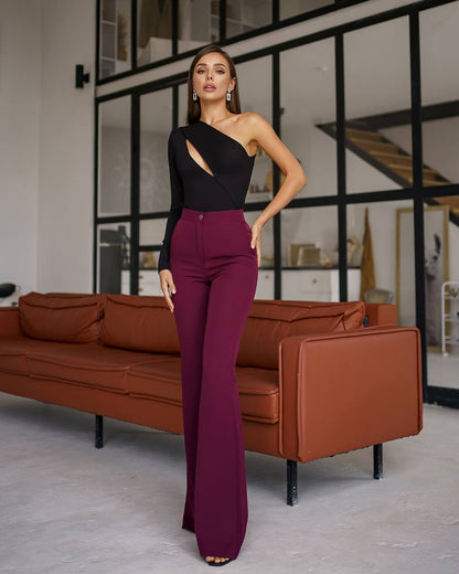 Woman in black top and purple pants standing in a modern living room.