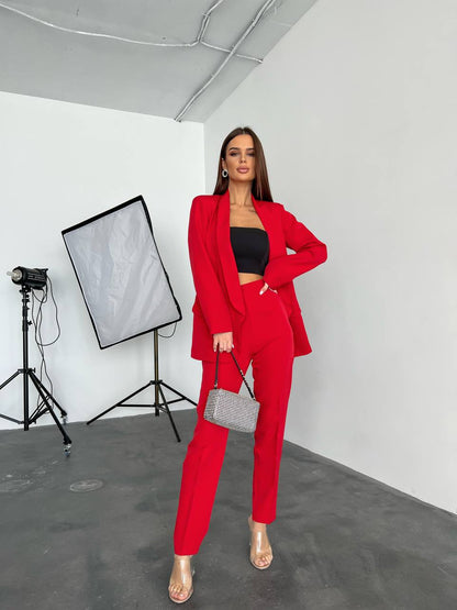 Woman in a red suit standing in a photo studio with lighting equipment.