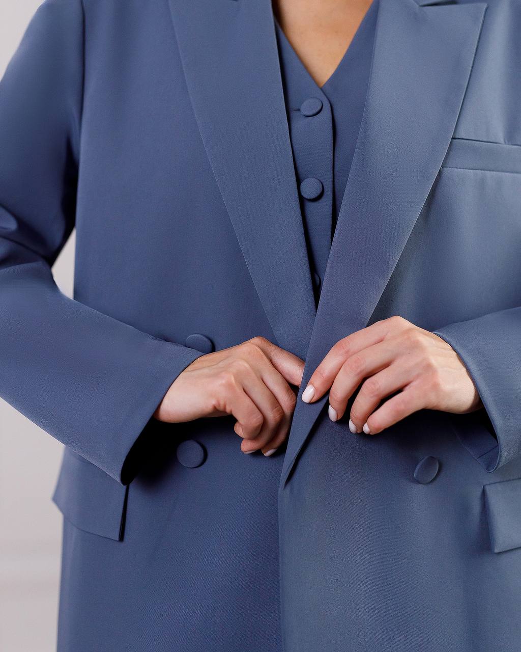Close-up of a person wearing a blue suit with hands adjusting the jacket.