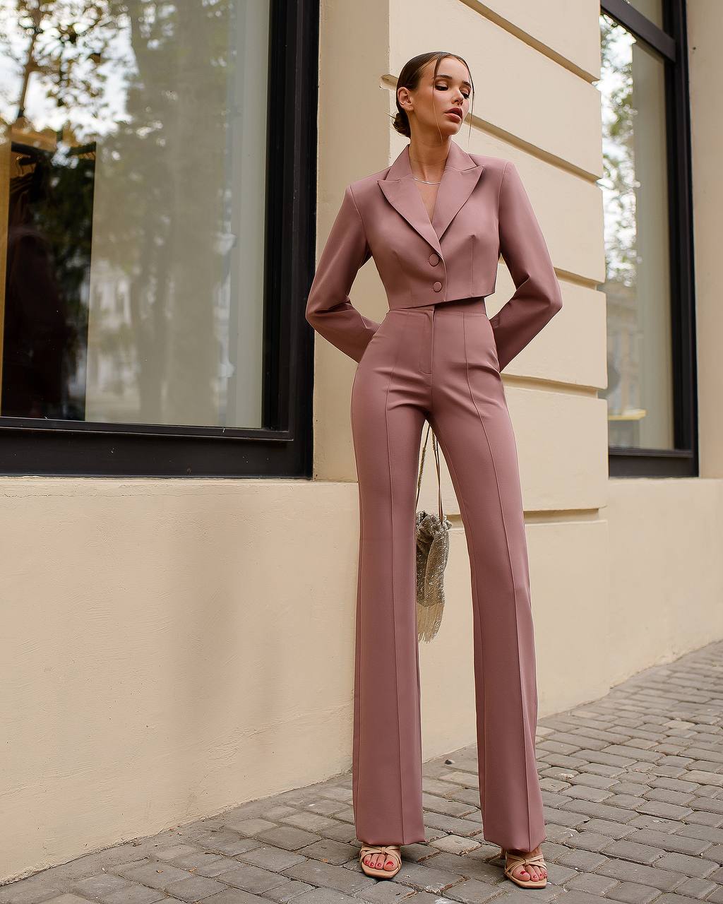 Woman in a pink suit standing on a street with a building in the background