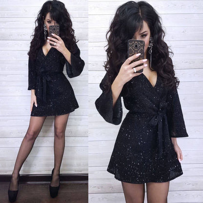 Woman wearing a black glittery dress against a white wooden panel background