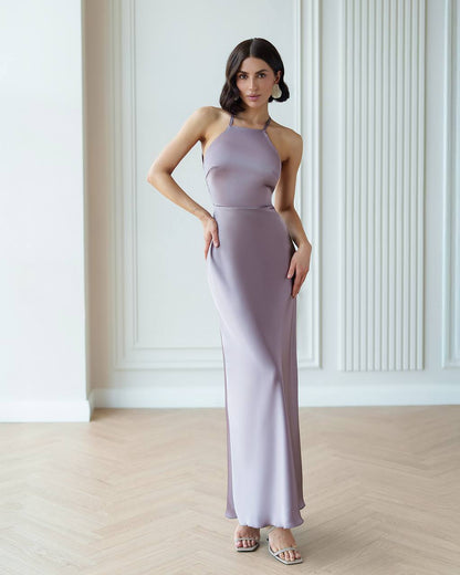 Woman wearing a long, light purple dress in a minimalistic room.
