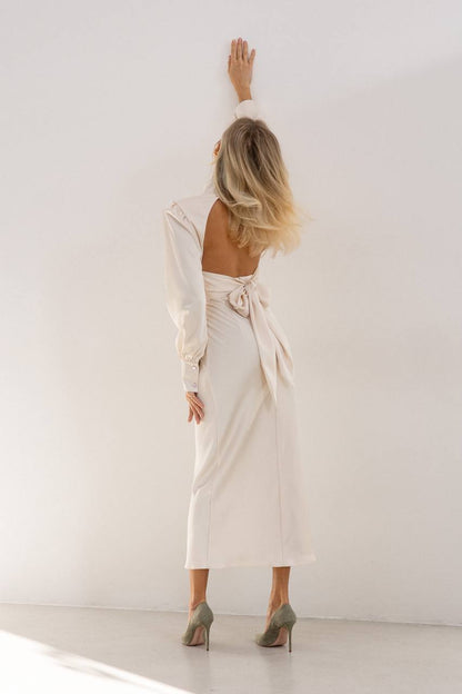 Woman in a white dress standing against a white wall