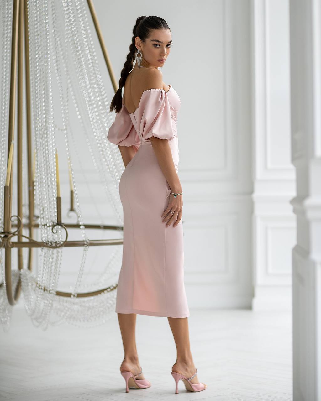 Woman wearing a pink off-shoulder dress in an elegant indoor setting.