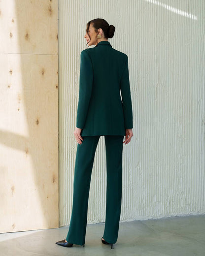 Woman wearing a green suit standing against a textured wall.