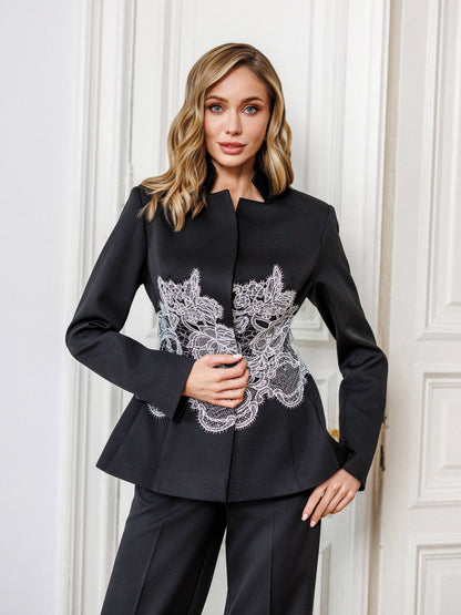 Woman wearing a black jacket with lace detailing against a white wall