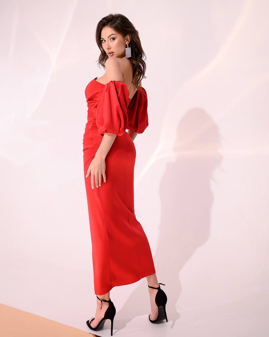 Woman wearing a red off-shoulder dress with a plain background