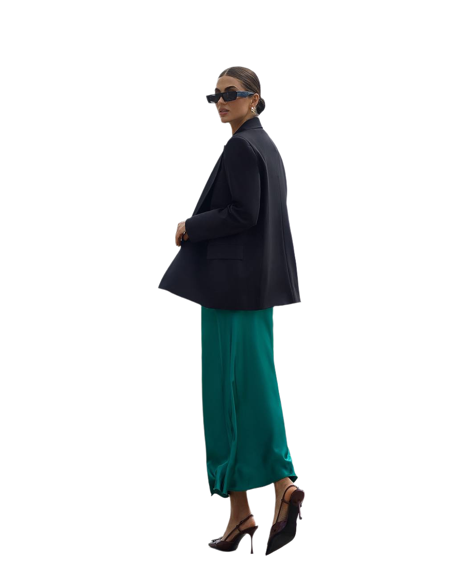 Woman wearing a black blazer and green skirt on a white background