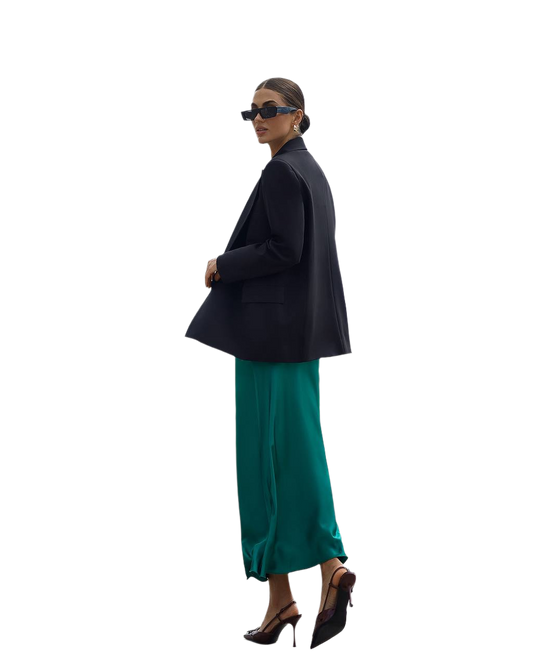 Woman wearing a black blazer and green skirt on a white background