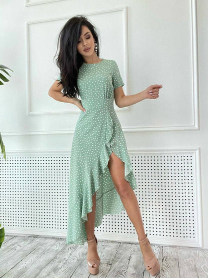 Woman wearing a green polka dot dress with a white wall background