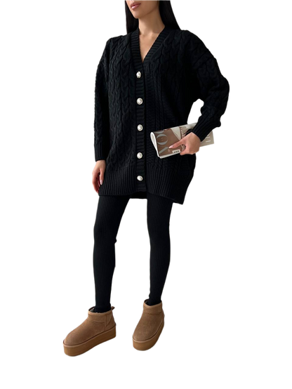 Person wearing a black cardigan, black leggings, and brown boots on a white background