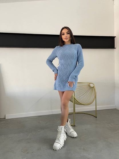 Woman wearing a blue knitted dress with white high-top sneakers in a minimalistic room.