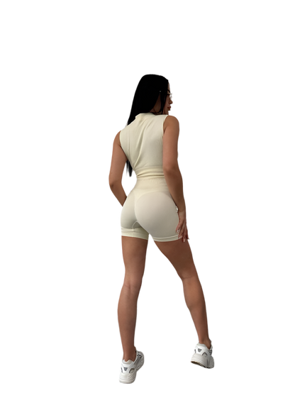 Woman wearing a beige sleeveless top and shorts set on a white background