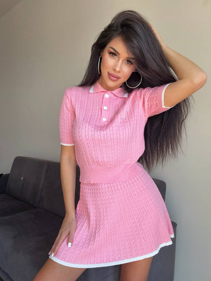Woman wearing a pink dress posing in a room with a gray couch.