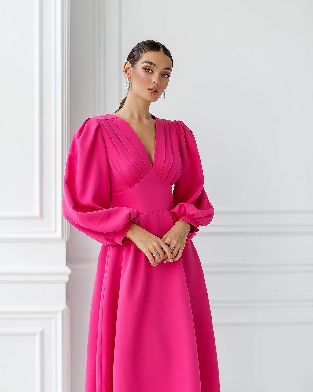 Woman wearing a bright pink dress against a white wall