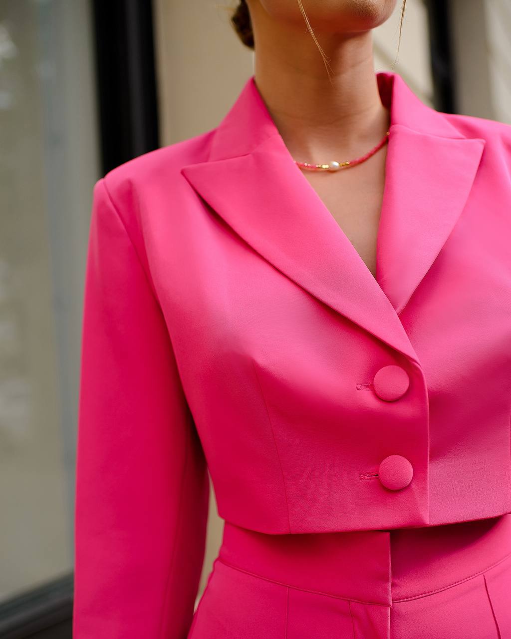 Close-up of a bright pink suit jacket with a blurred background