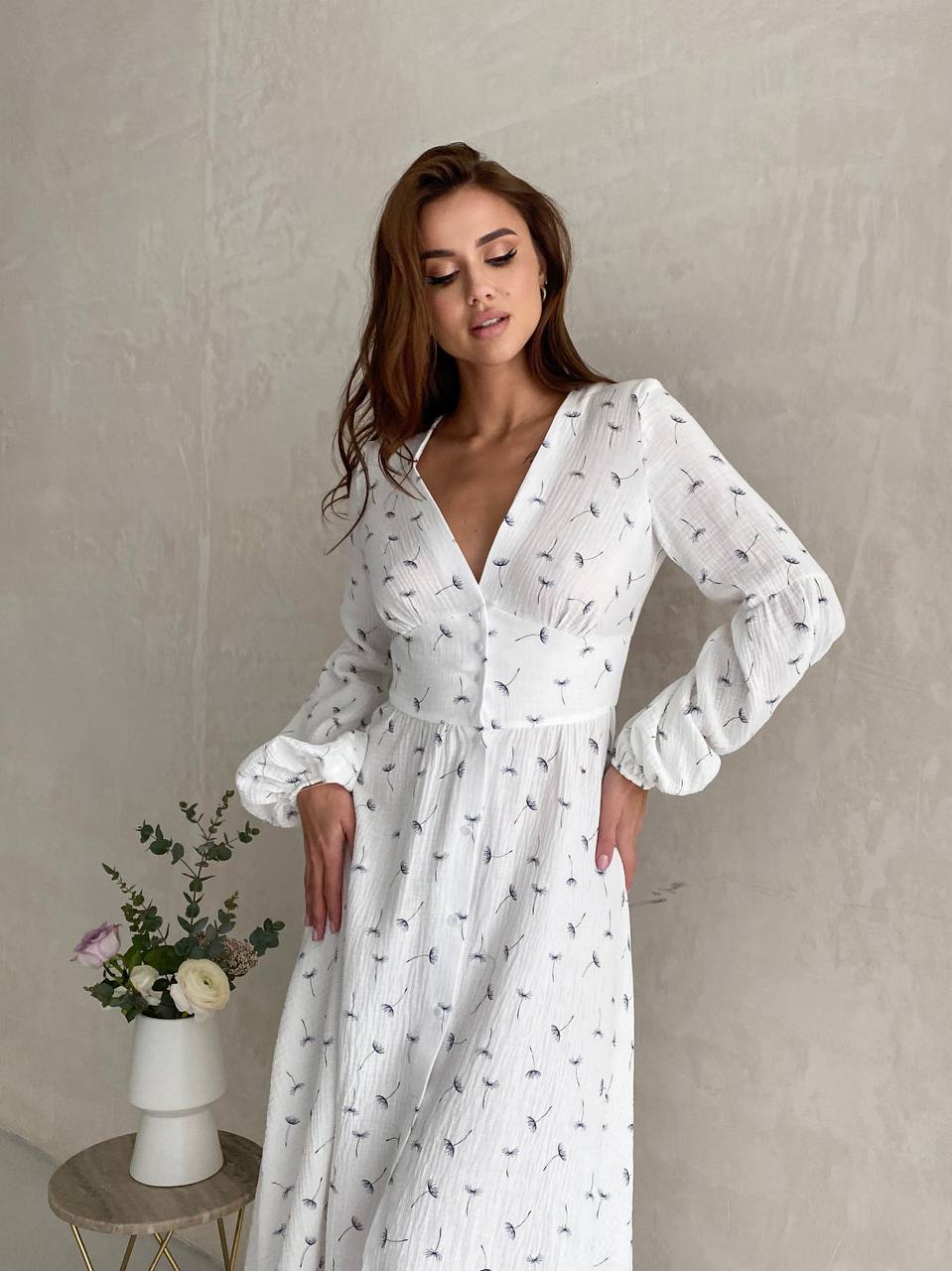 Woman wearing a white dress with long sleeves against a plain background