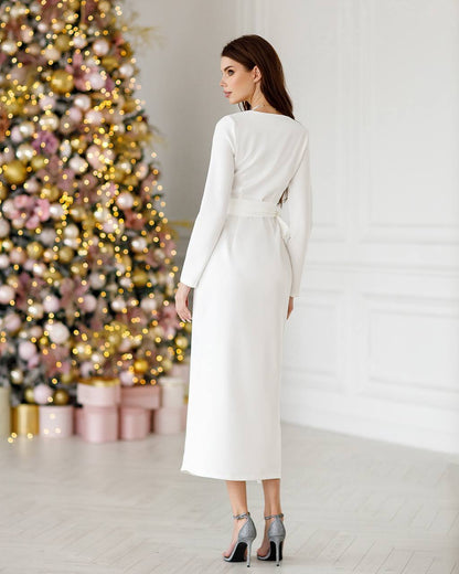 Woman in a white dress standing in front of a decorated Christmas tree.