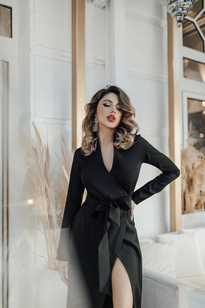 Woman in a black dress posing indoors with decorative elements.