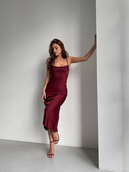 Woman in a burgundy dress standing against a plain background