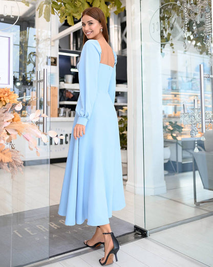 Woman in a light blue dress standing in a modern interior setting