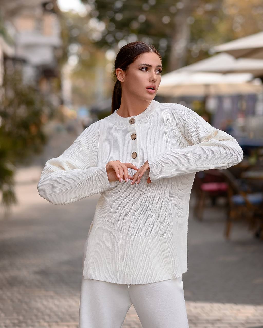 Woman wearing a white sweater with button details outdoors