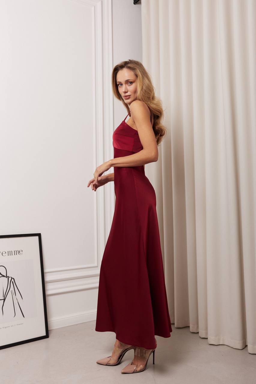 Woman in a red dress standing in a room with white walls and curtains.