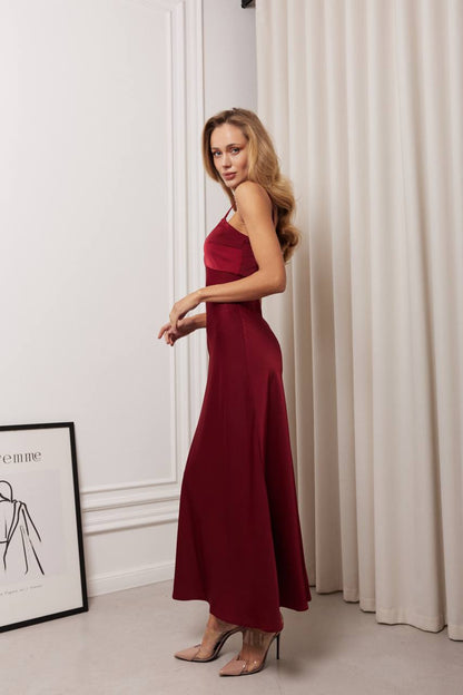 Woman in a red dress standing in a room with white walls and curtains.
