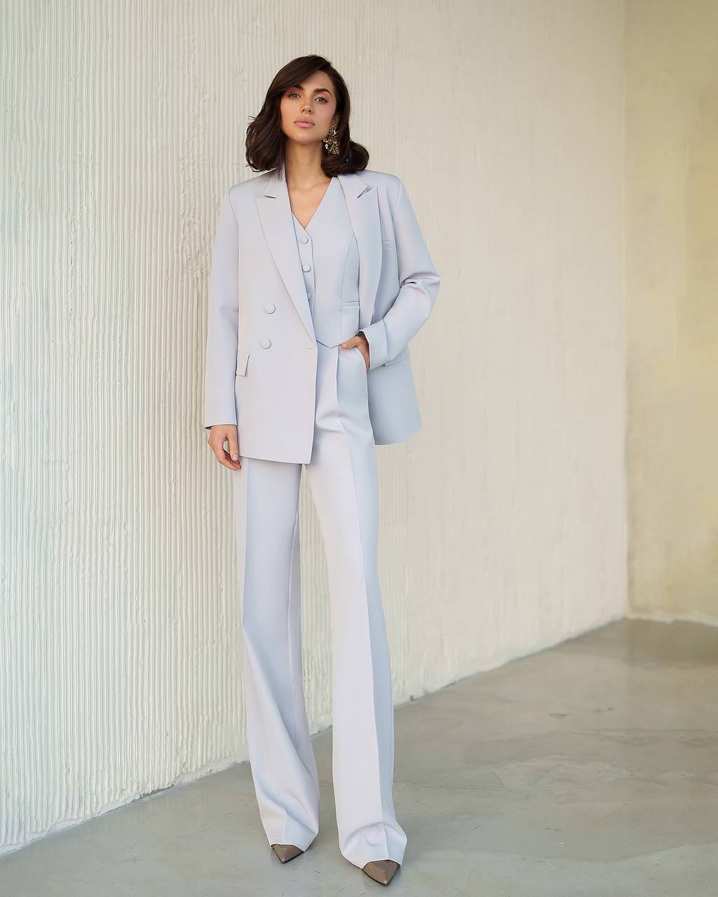 Woman wearing a light blue suit standing against a neutral background