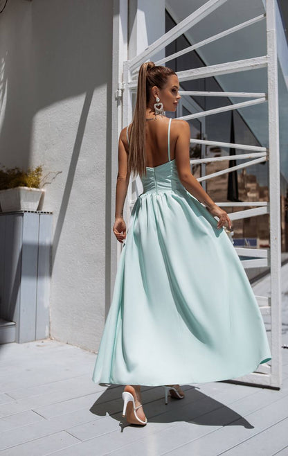 Woman in a light blue dress standing in front of a white metal staircase.