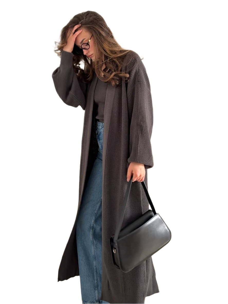 Woman wearing a long dark coat holding a black handbag on a white background