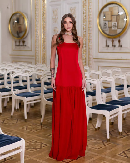 Woman in a red dress standing in an elegant room with white chairs and gold decorations.